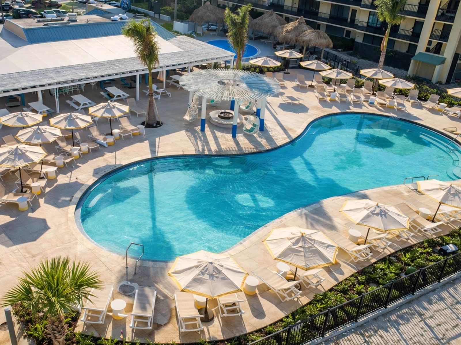 Beachfront resort swimming pool overlooking ocean shoreline with guests relaxing poolside