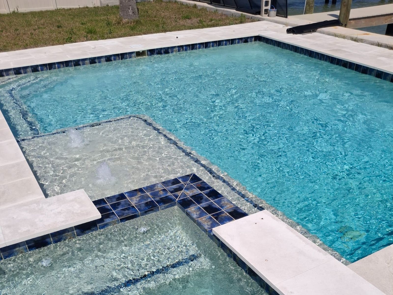 A sparkling blue swimming pool features clear water and subtle fountains, surrounded by modern tile and concrete finishes.
