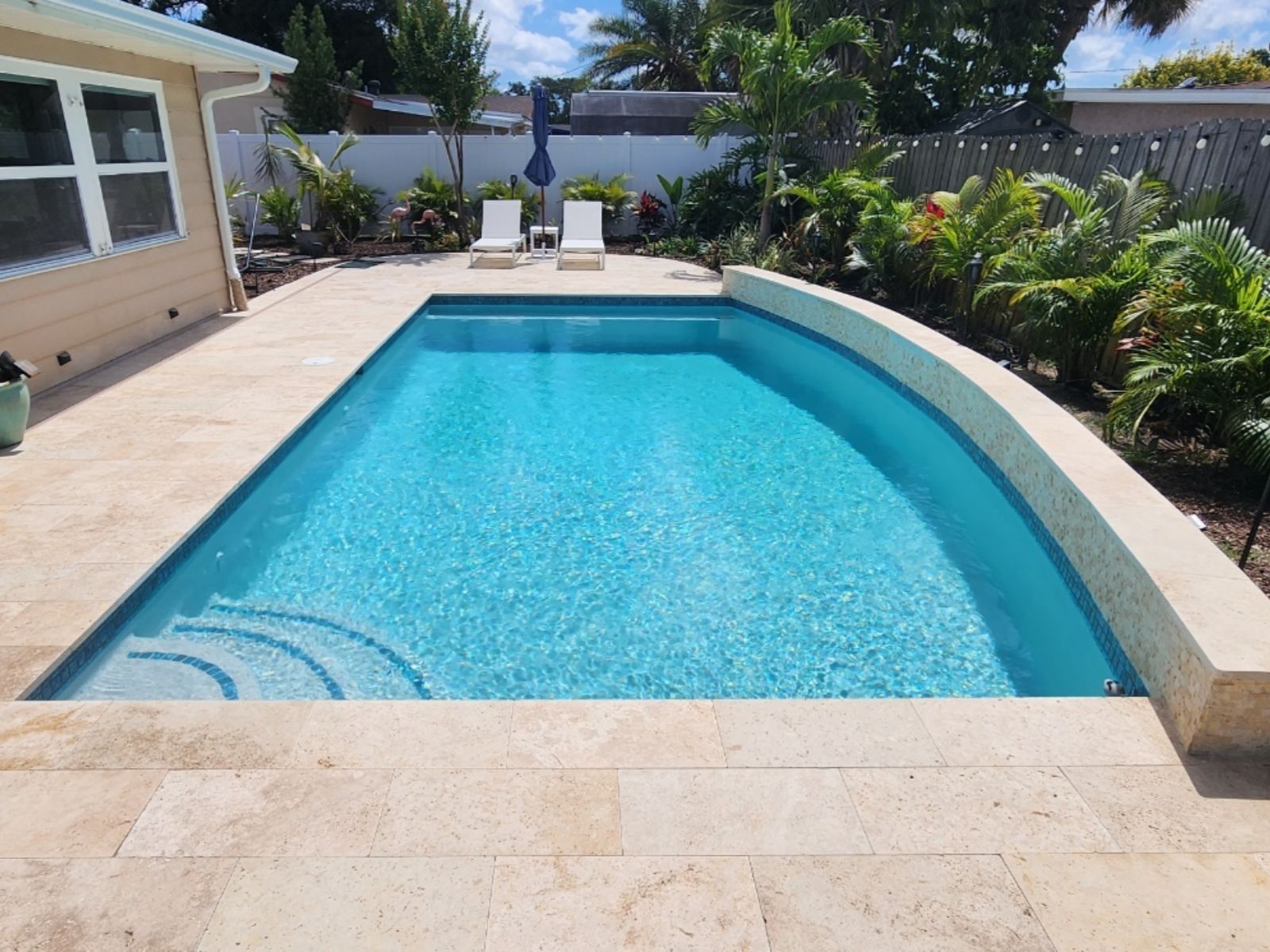 Bright blue swimming pool surrounded by sunny patio, palm trees, and loungers, creating a relaxing outdoor oasis.