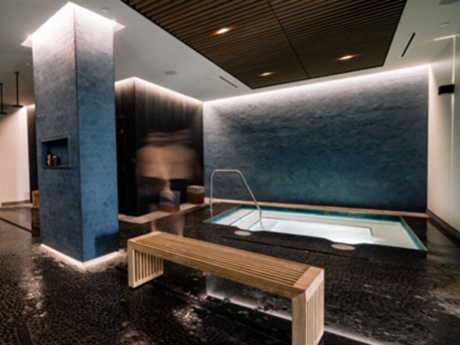 Luxury indoor spa and wellness pool with contemporary design, soft lighting, and relaxation bench