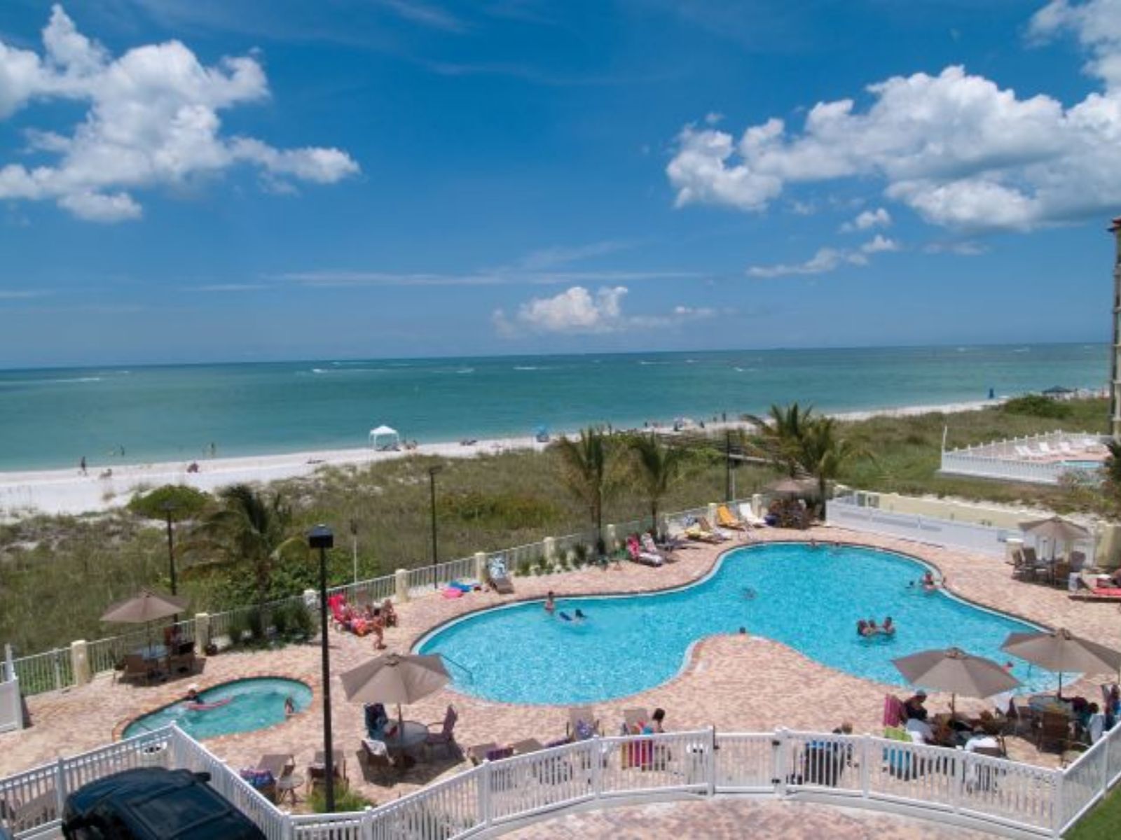 Beachfront resort swimming pool overlooking ocean shoreline with guests relaxing poolside
