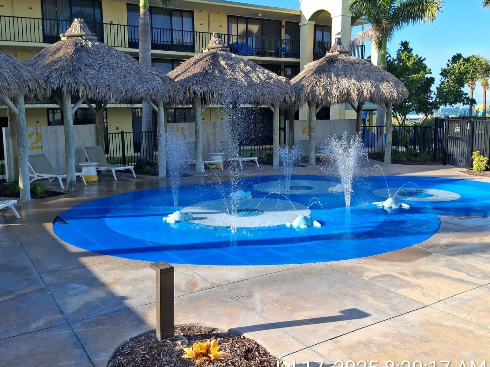 Resort splash pad with water fountains and shaded tiki huts for children and families