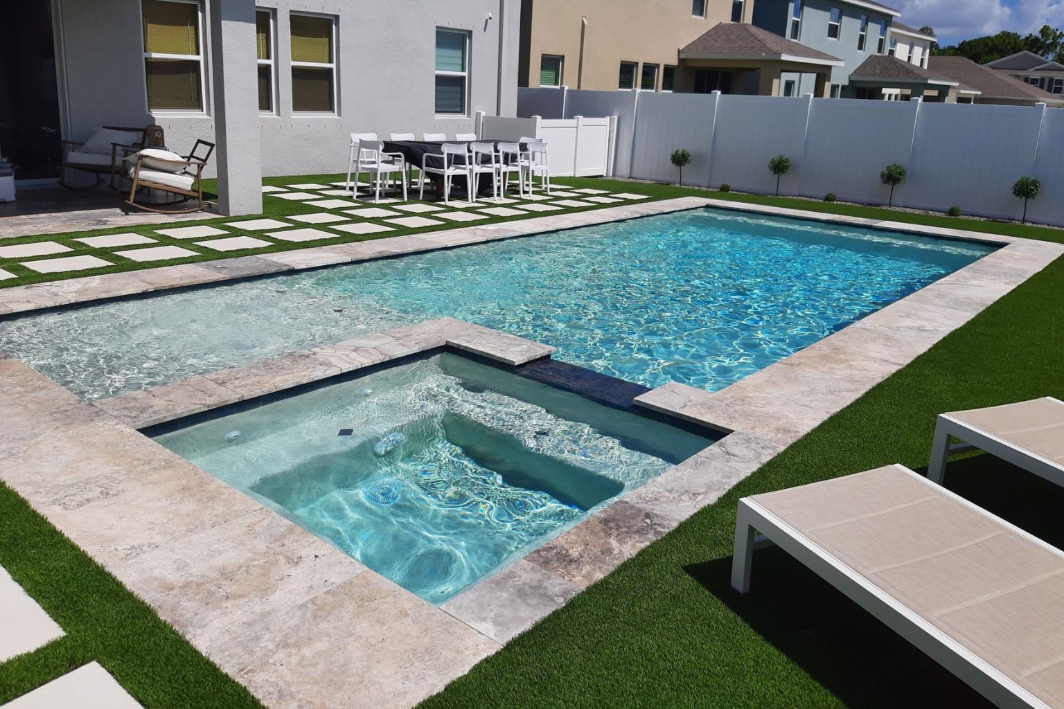 How to Choose the Best Pool Vacuum Cleaners: Expert Reviews & Buying Guide 3 A clean and clear pool with a connected hot tub, surrounded by manicured landscaping and modern patio furniture in a residential backyard.